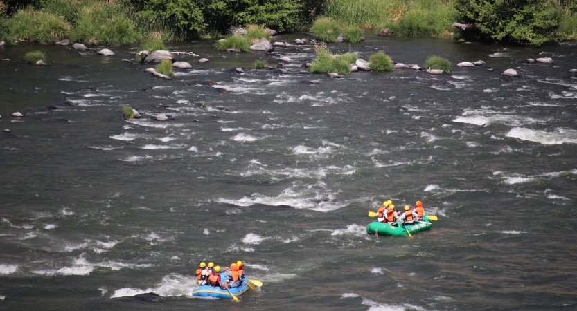 From an aerial point of view, two rafts containing people float along a river